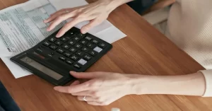 Hand holding a pen and pointing at financial charts on a printed report.