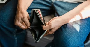 Person holding an empty wallet symbolizing financial struggle or lack of savings.